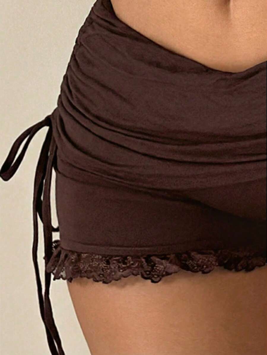 Black Y2K mini shorts with drawstring elastic waist, contrast lace, cut-out details, and ruffled hem