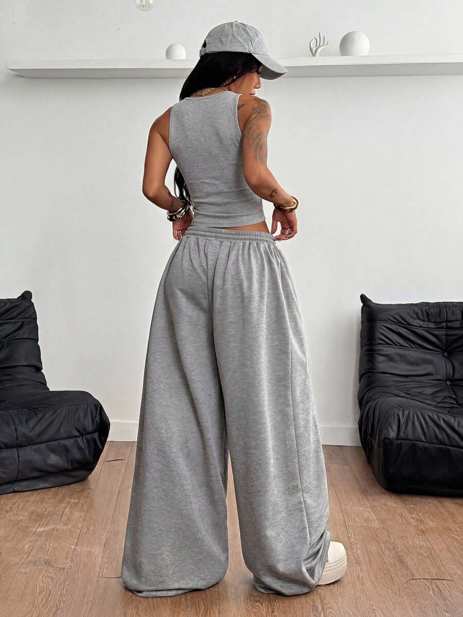 Women's two-piece casual outfit featuring a slim-fit camisole tank top with ruffle trim and button front paired with high-waisted wide leg pants.