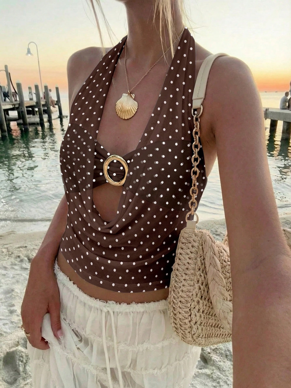 Brown and white polka dot semi-sheer halter camisole top with a plunging neckline, backless design, draped front, and metallic studded embellishments.