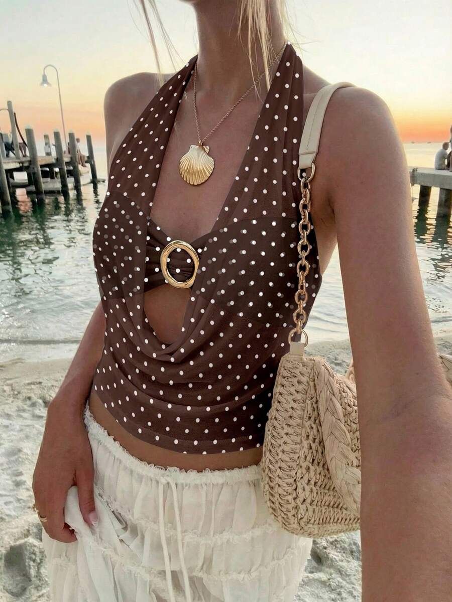 Brown and white polka dot semi-sheer halter camisole top with a plunging neckline, backless design, draped front, and metallic studded embellishments.