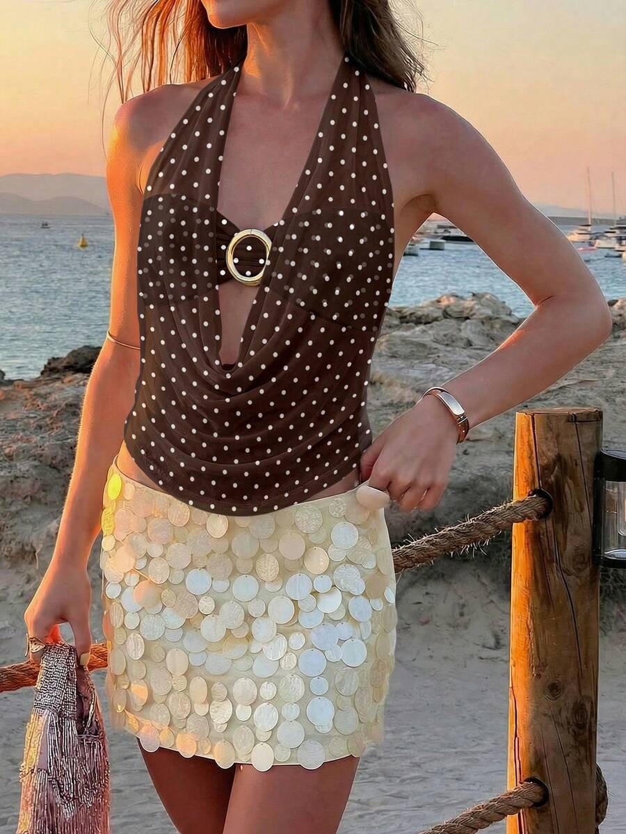 Brown and white polka dot semi-sheer halter camisole top with a plunging neckline, backless design, draped front, and metallic studded embellishments.