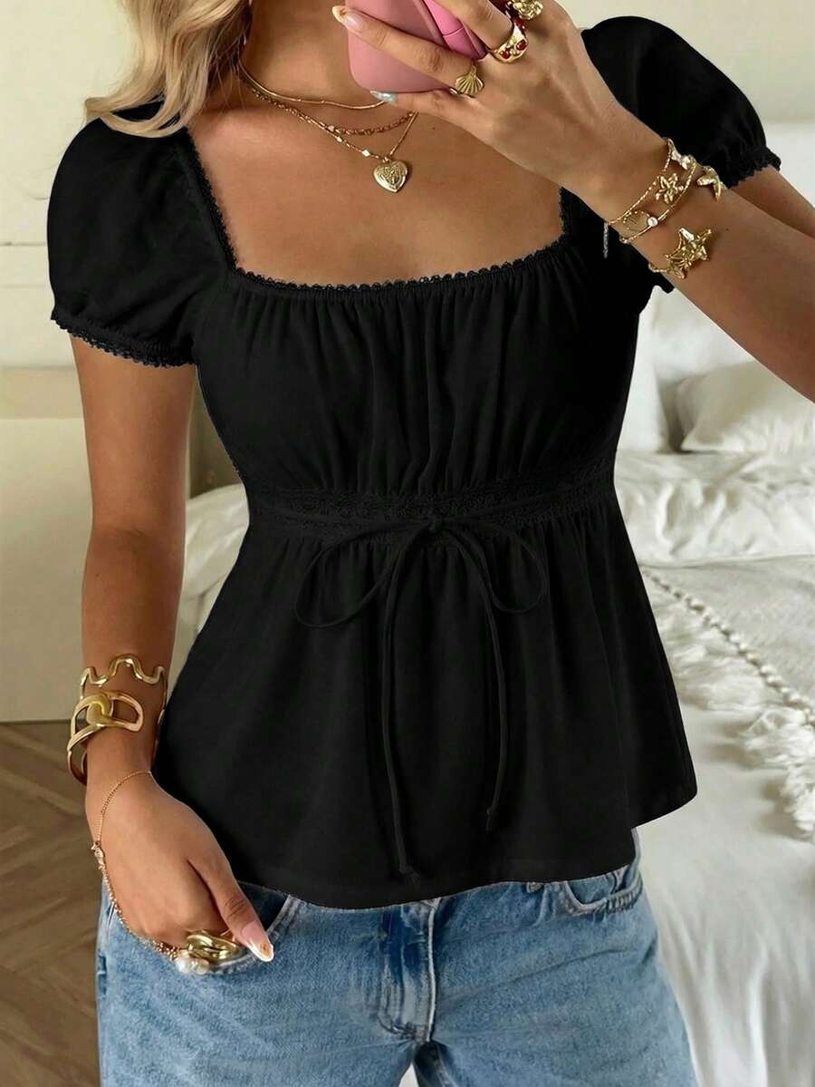 Women's black short puff sleeve top featuring a square neckline, ruched bust detail, and flared ruffle hem.