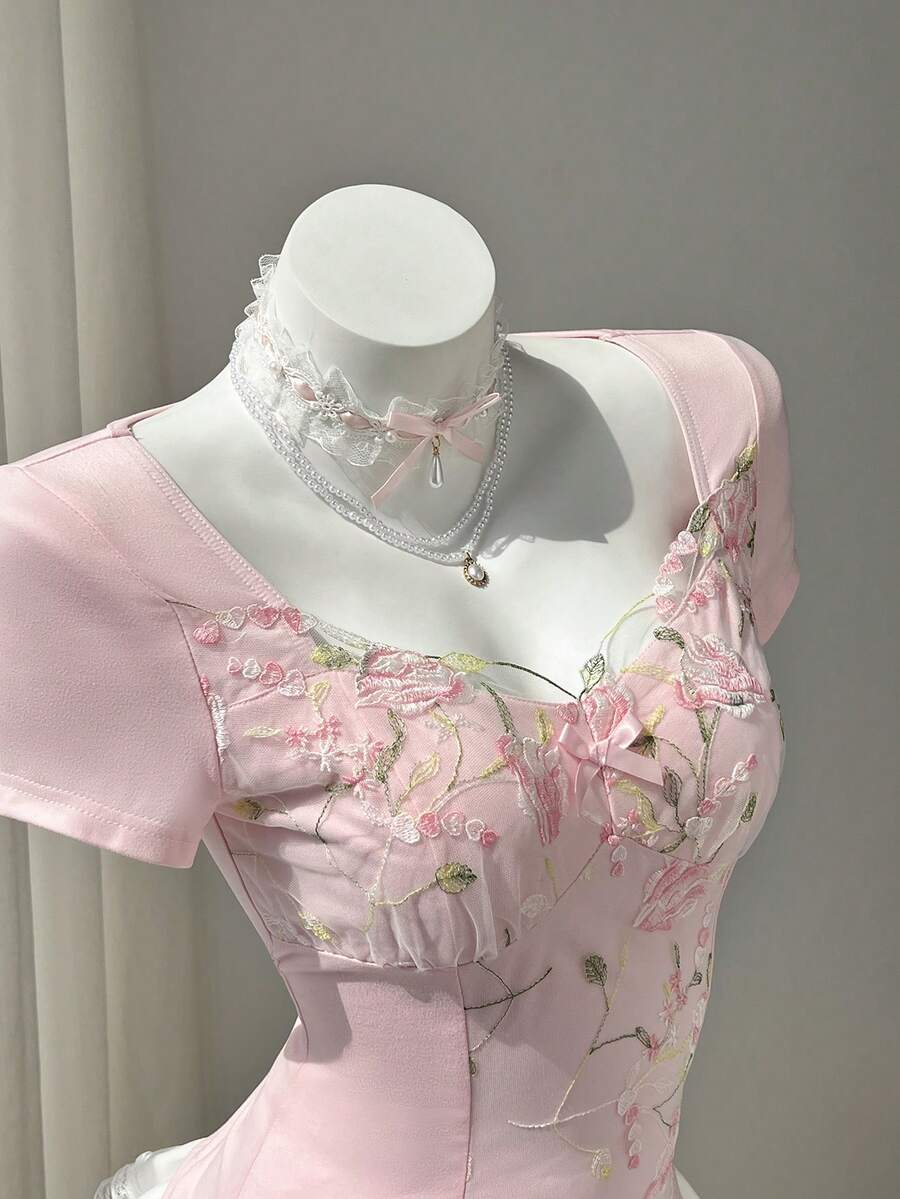 Women's pink short sleeve slim fit dress featuring a plant pattern, scoop neck, ruched appliques, and button front detail.