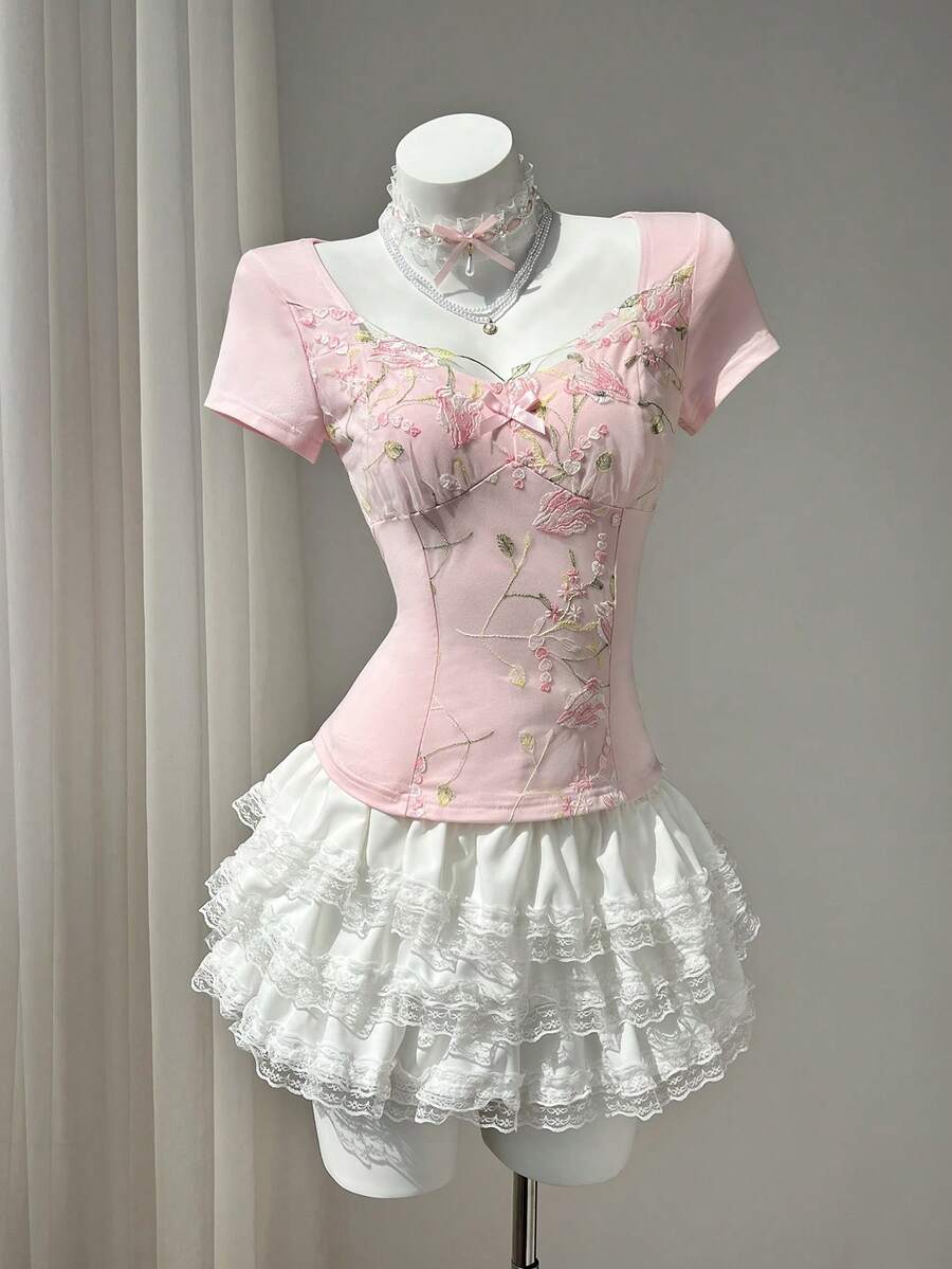 Women's pink short sleeve slim fit dress featuring a plant pattern, scoop neck, ruched appliques, and button front detail.