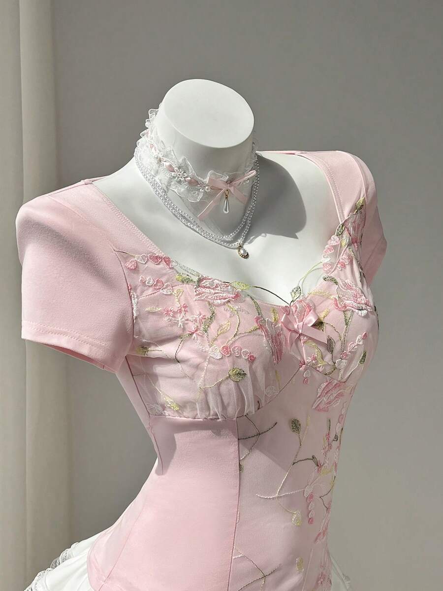 Women's pink short sleeve slim fit dress featuring a plant pattern, scoop neck, ruched appliques, and button front detail.