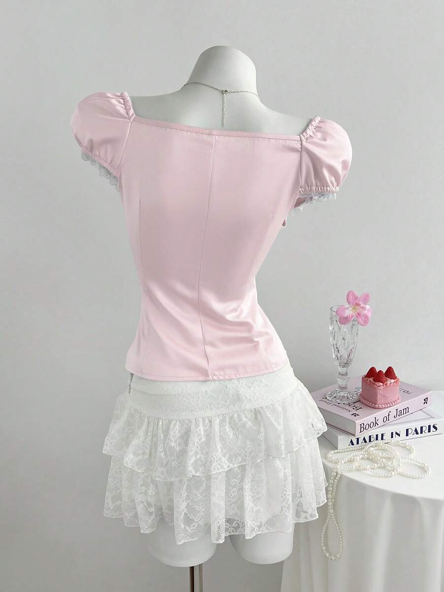 Women's black 2-in-1 blouse featuring a sweetheart neckline, short puff sleeves, front tie bow accent, and asymmetrical hem.