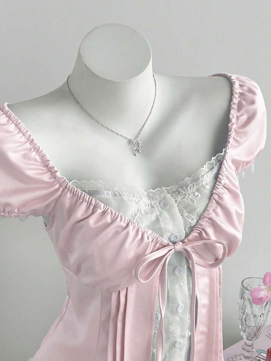Women's black 2-in-1 blouse featuring a sweetheart neckline, short puff sleeves, front tie bow accent, and asymmetrical hem.