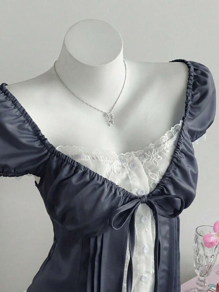 Women's black 2-in-1 blouse featuring a sweetheart neckline, short puff sleeves, front tie bow accent, and asymmetrical hem.