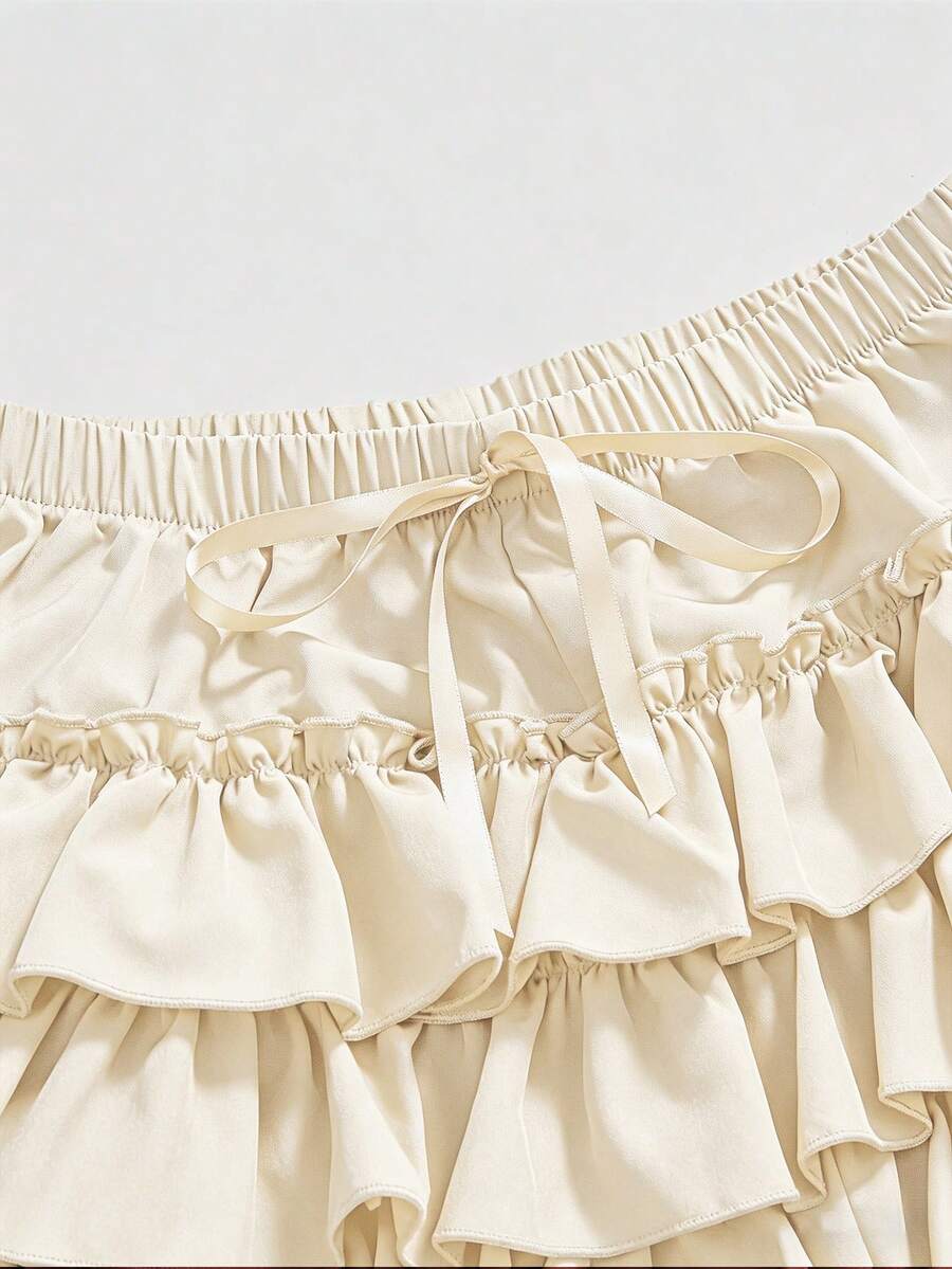 Women's tiered ruffle skort shorts featuring an elastic mid waist with front tie knot detail in woven fabric.