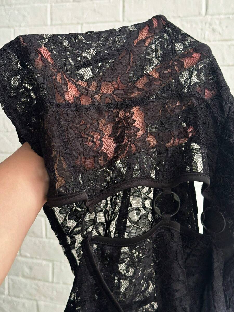 Women's black slim fit semi-sheer blouse featuring contrast lace detailing, a deep V hollow design with ring accent, asymmetrical hem, and cap sleeves.