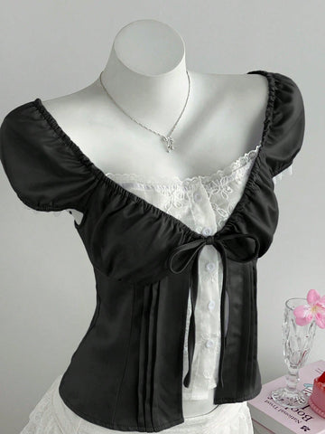Women's black 2-in-1 blouse featuring a sweetheart neckline, short puff sleeves, front tie bow accent, and asymmetrical hem.