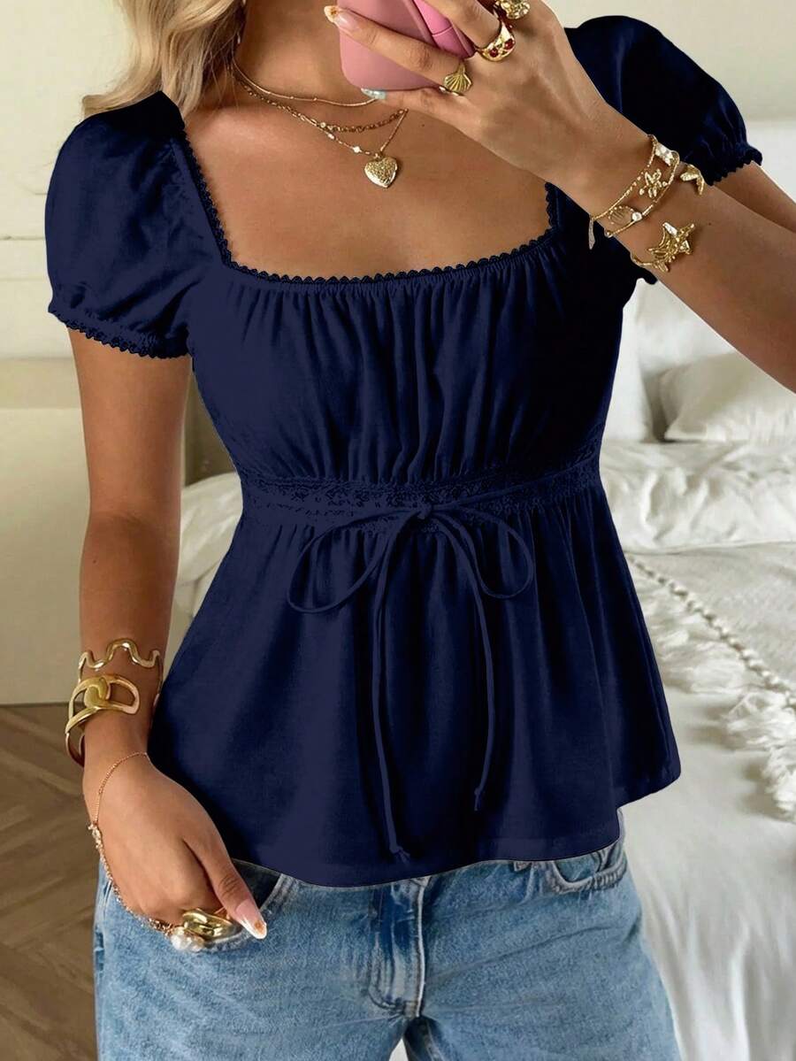 Women's black short puff sleeve top featuring a square neckline, ruched bust detail, and flared ruffle hem.