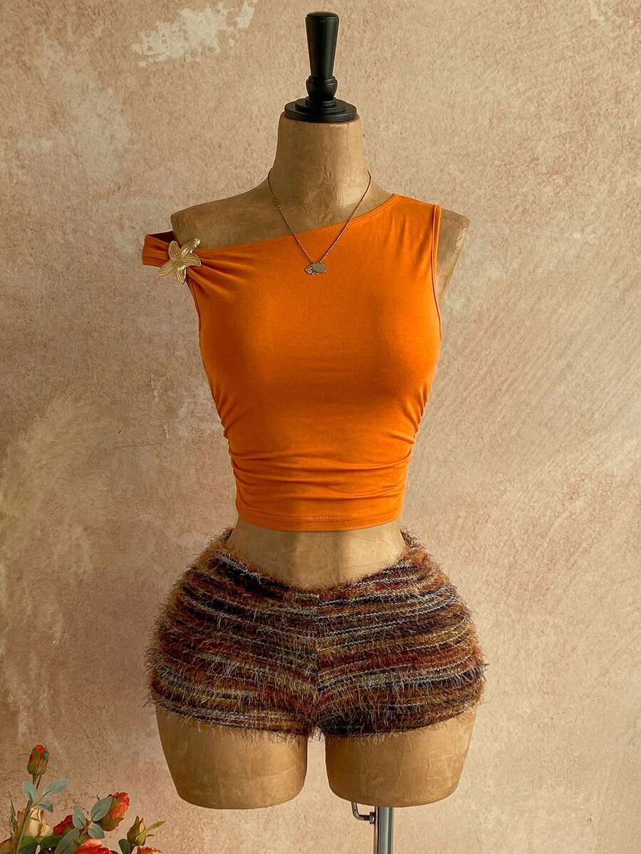 Women's black fuzzy knit two-piece set with an asymmetrical crop camisole top featuring ruched detail and cutout back, paired with matching mini shorts.