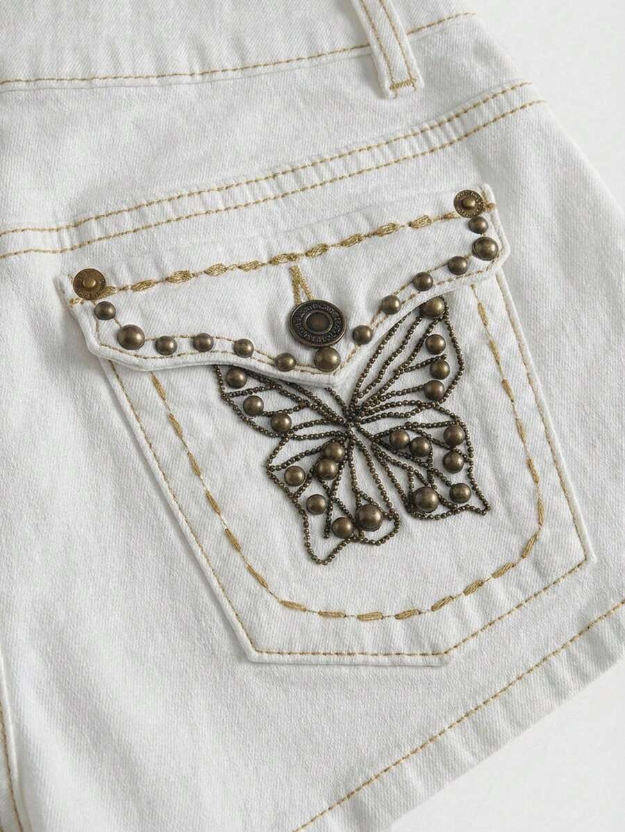 Women's Y2K low waist distressed shorts featuring butterfly studded details, pockets, and a zipper fly closure.