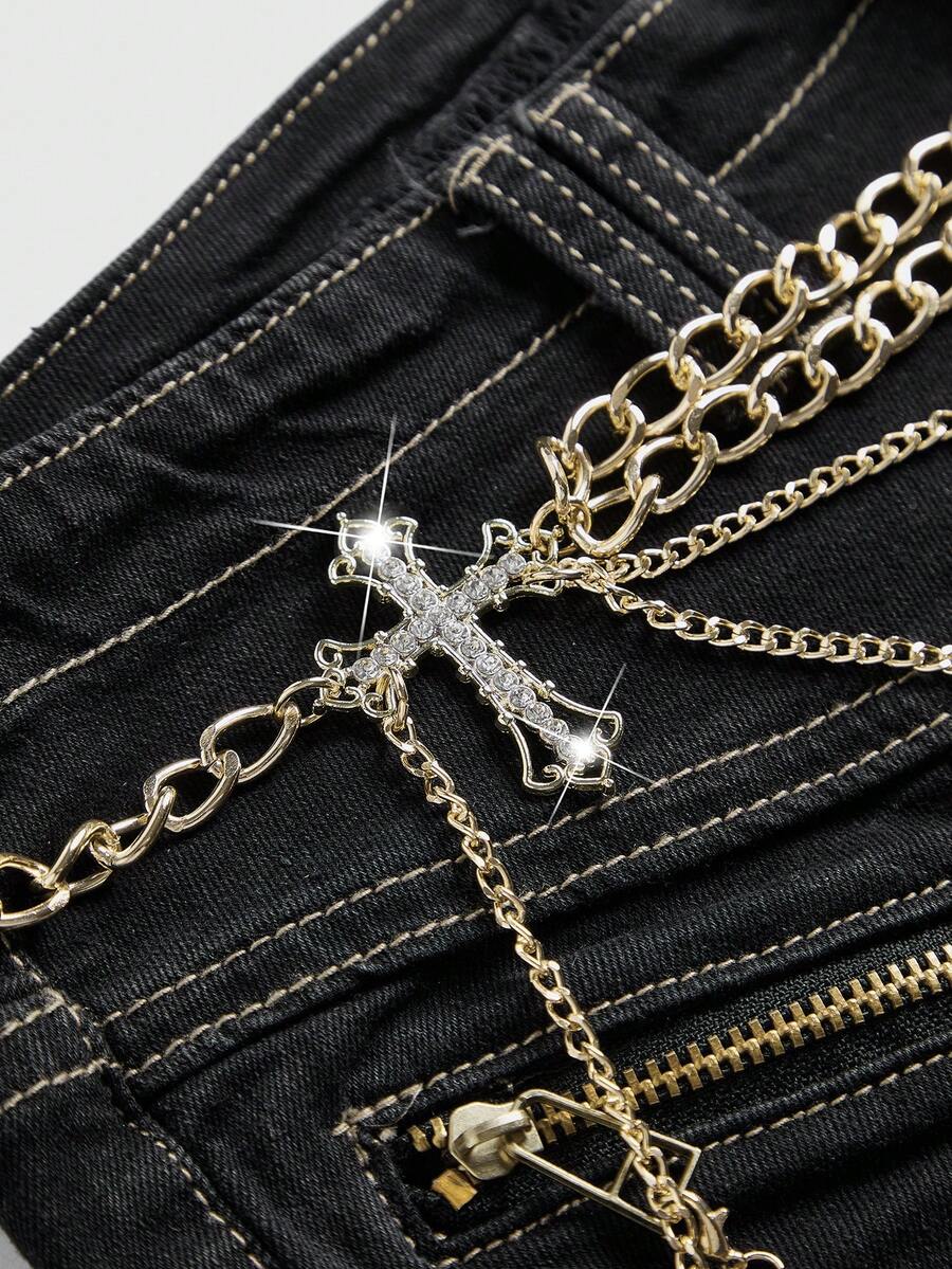 Ultra low-rise stretch denim mini shorts featuring a metal chain with cross pendant and rhinestone detailing.