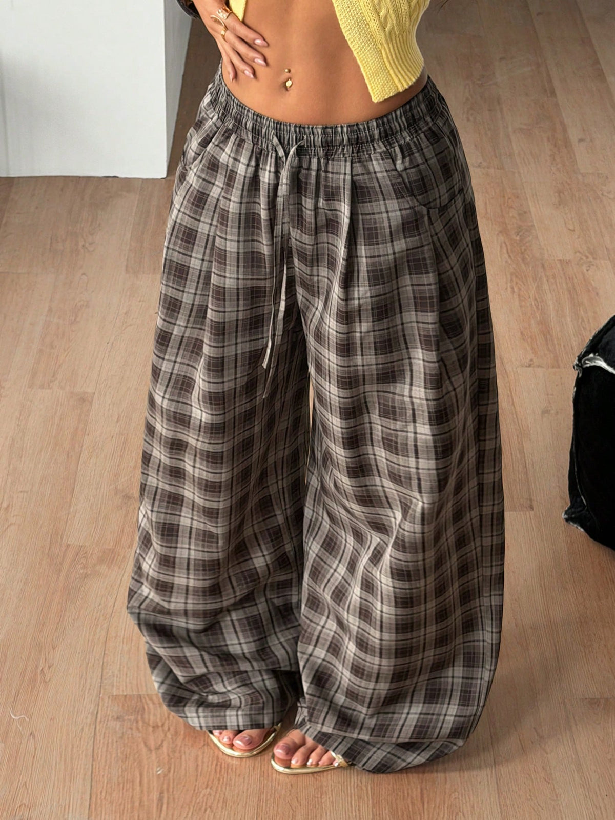 Women's loose fit brown and tan plaid wide leg pants featuring an elastic drawstring waist and side pockets.