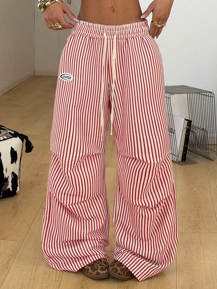 Women's black and white striped wide leg pants featuring an elastic drawstring waistband, side pockets, and a loose straight leg fit.