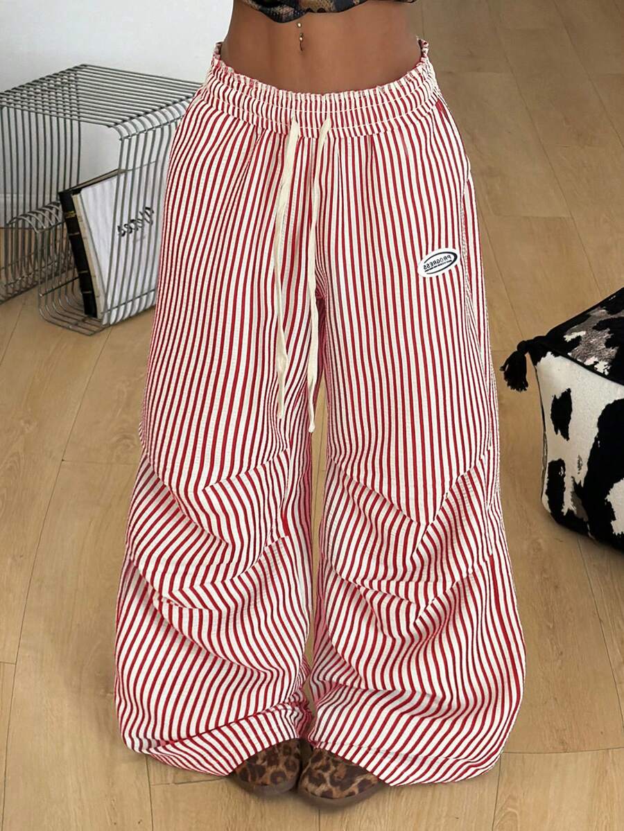 Women's black and white striped wide leg pants featuring an elastic drawstring waistband, side pockets, and a loose straight leg fit.
