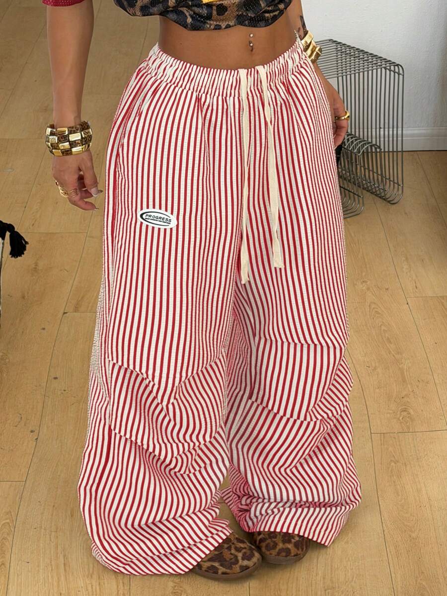 Women's black and white striped wide leg pants featuring an elastic drawstring waistband, side pockets, and a loose straight leg fit.