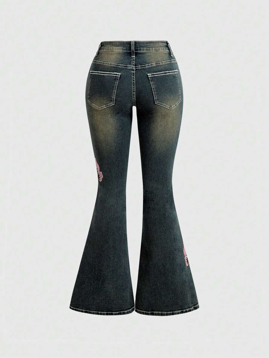 Women's blue ultra low waist flare jeans with butterfly vine embroidery and rhinestone detailing on stretch denim.