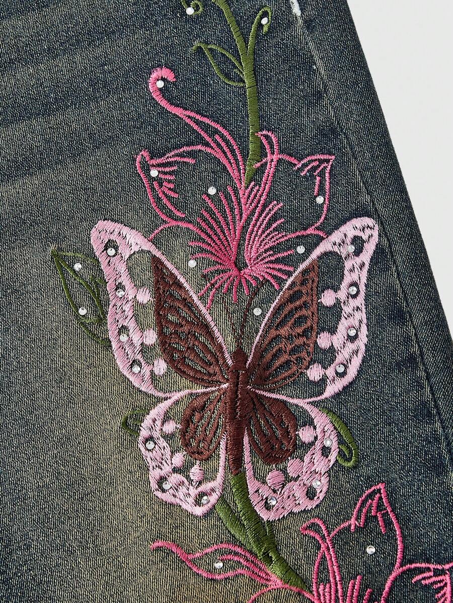 Women's blue ultra low waist flare jeans with butterfly vine embroidery and rhinestone detailing on stretch denim.