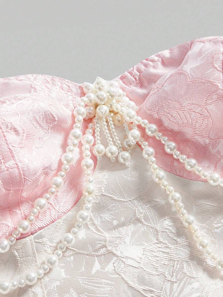Women's apricot strapless vintage palace style blouse featuring an asymmetrical ruffle hem, backless design, and pearl brooch detail.