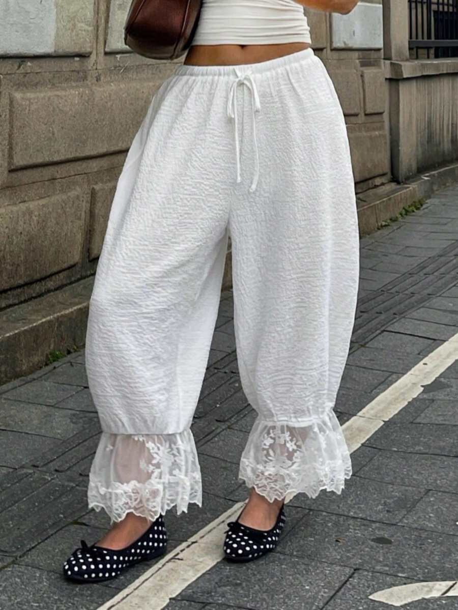 Women's loose-fitting lantern bloomer pants in capri length featuring delicate contrast lace trim and a drawstring waist.