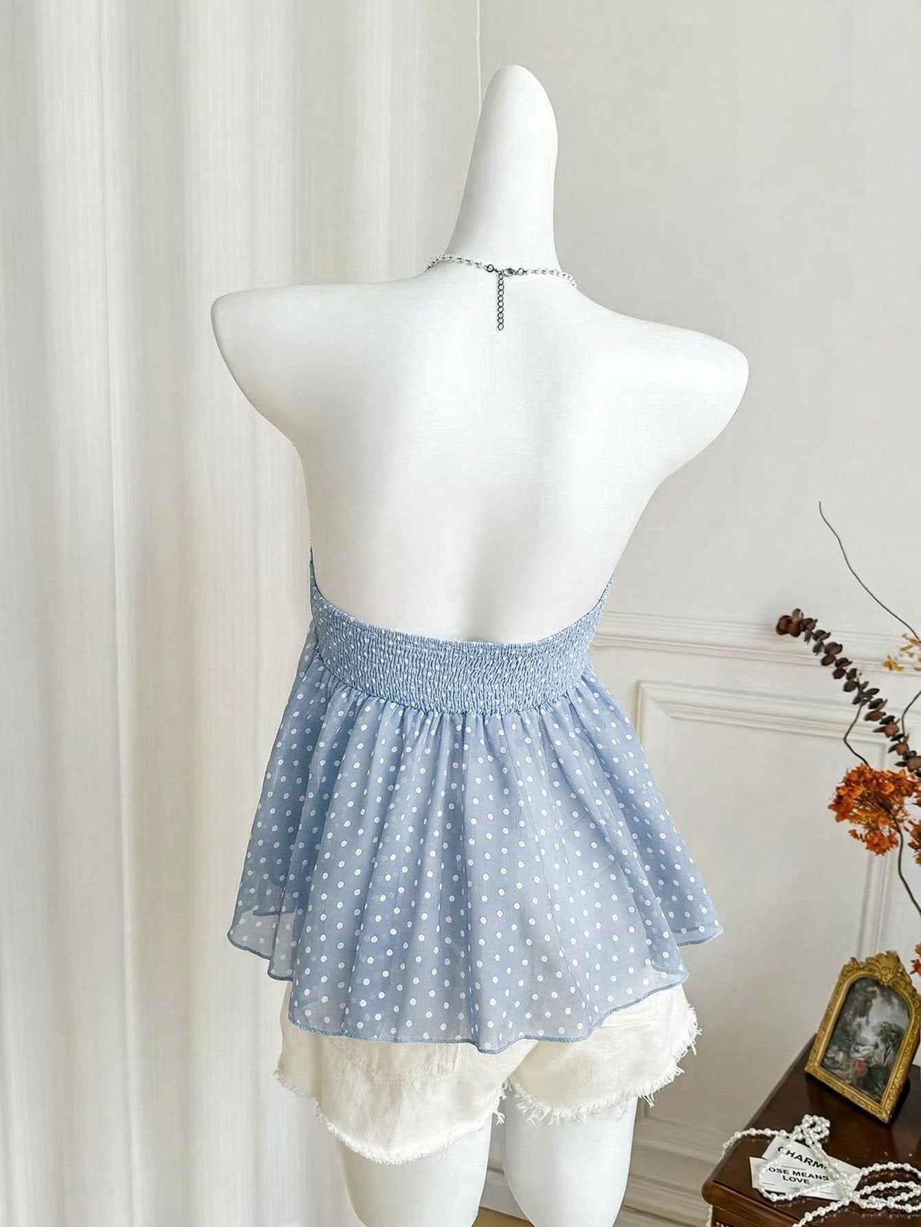 Women's polka dot strapless bandeau crop top with tie bow detail, asymmetrical shirring, and a flared hem.