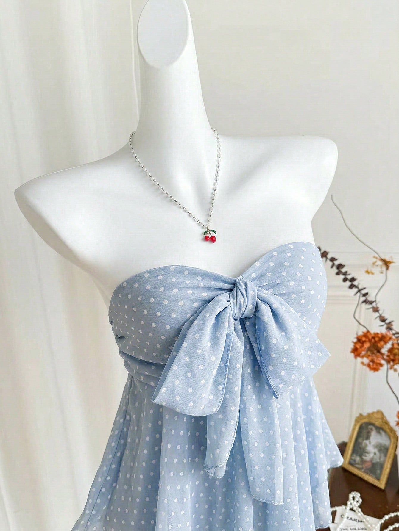 Women's polka dot strapless bandeau crop top with tie bow detail, asymmetrical shirring, and a flared hem.