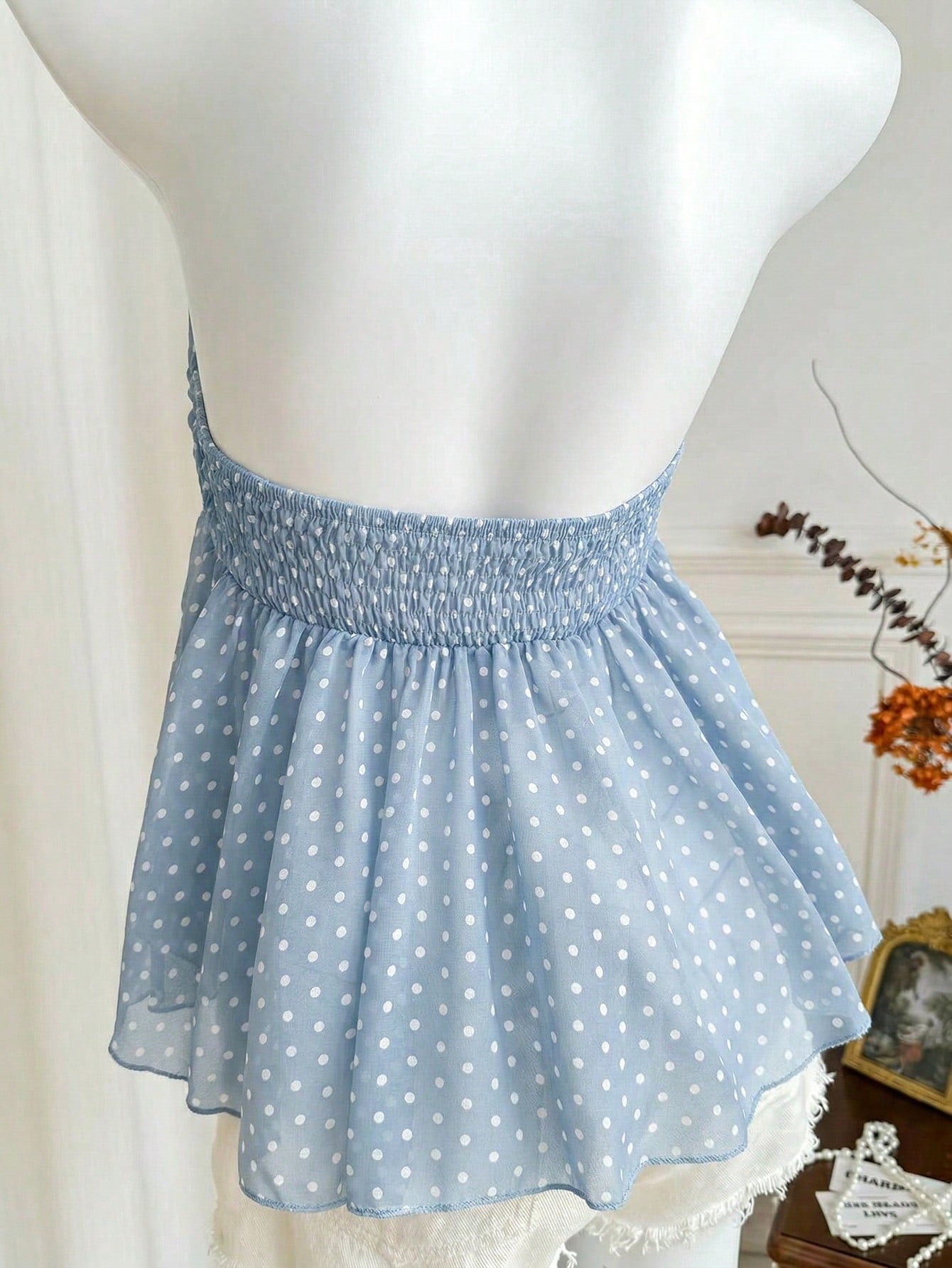 Women's polka dot strapless bandeau crop top with tie bow detail, asymmetrical shirring, and a flared hem.