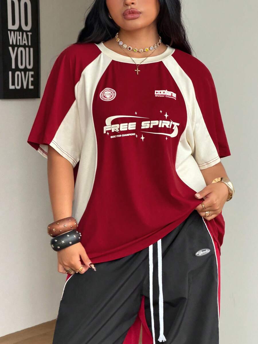 Unisex plus size oversized jersey t-shirt in brown featuring a round neck, short raglan sleeves with contrast binding, and a front letter graphic print.