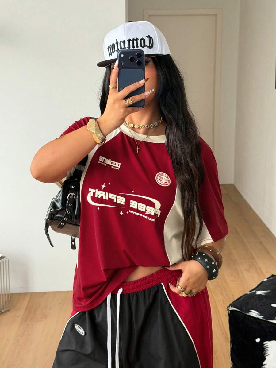 Unisex plus size oversized jersey t-shirt in brown featuring a round neck, short raglan sleeves with contrast binding, and a front letter graphic print.