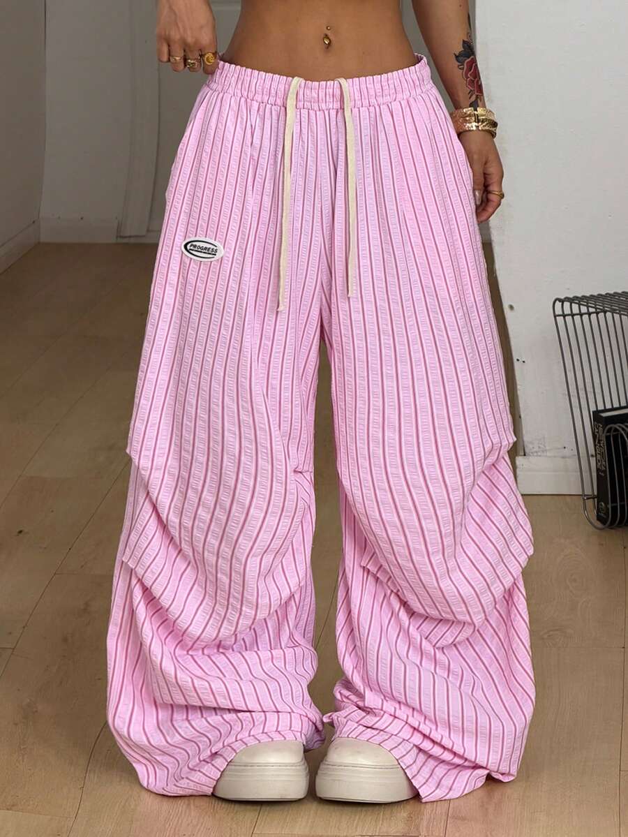 Women's black and white striped wide leg pants featuring an elastic drawstring waistband, side pockets, and a loose straight leg fit.