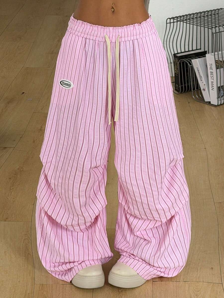 Women's black and white striped wide leg pants featuring an elastic drawstring waistband, side pockets, and a loose straight leg fit.
