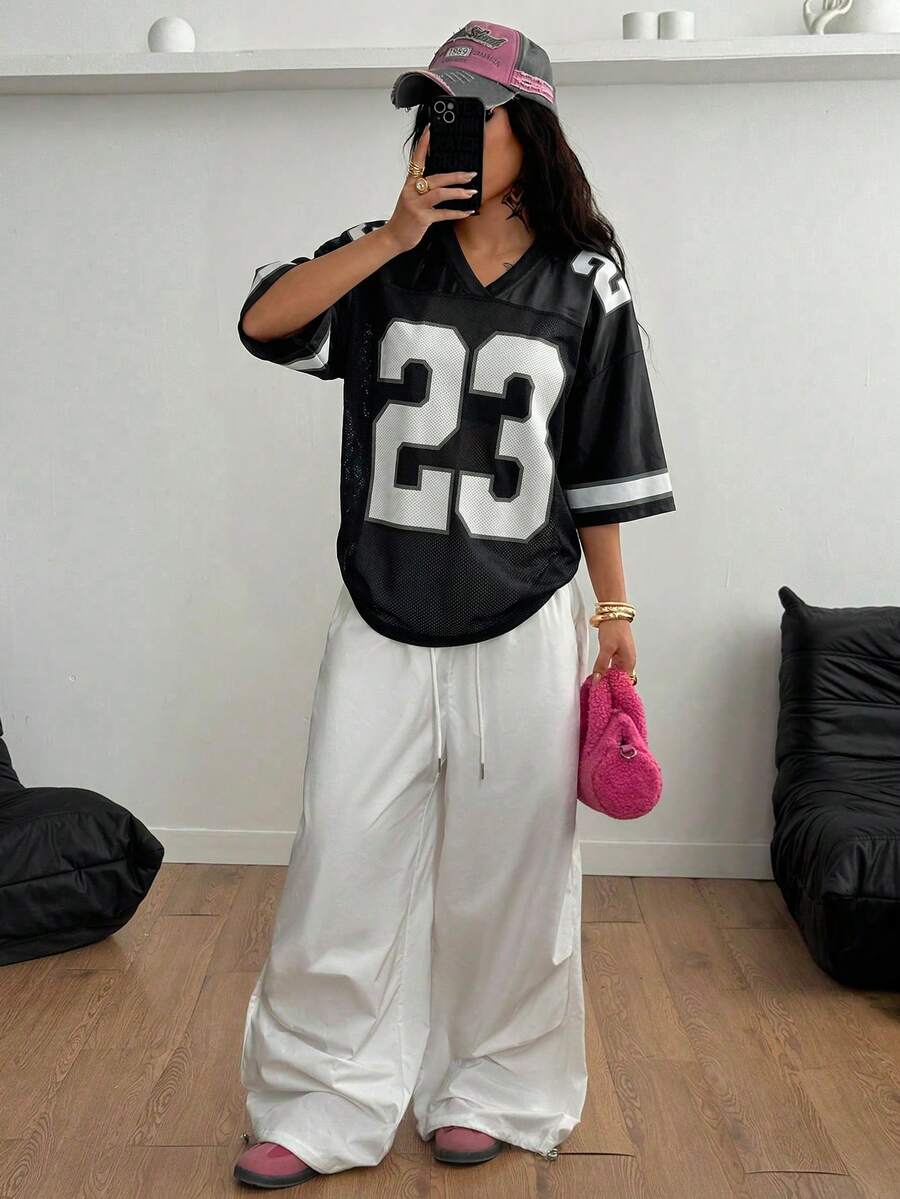 Oversized short-sleeve football jersey top featuring a V-neckline, contrast binding, and graphic number print.