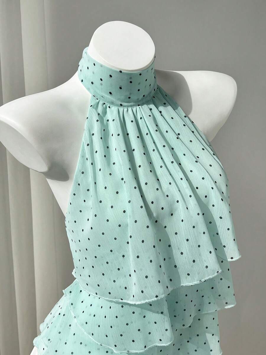 Women's white sleeveless halter neck top featuring pleated fabric, backless tie strap design, and a flared layered ruffle hem.