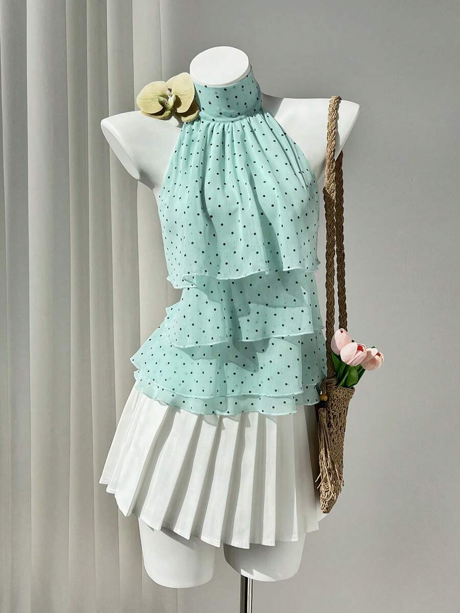 Women's white sleeveless halter neck top featuring pleated fabric, backless tie strap design, and a flared layered ruffle hem.