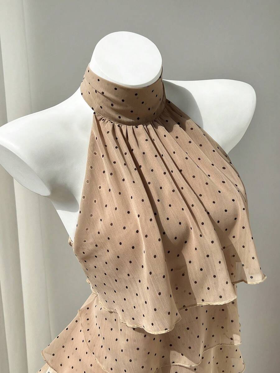 Women's white sleeveless halter neck top featuring pleated fabric, backless tie strap design, and a flared layered ruffle hem.