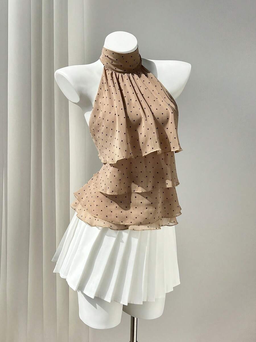 Women's white sleeveless halter neck top featuring pleated fabric, backless tie strap design, and a flared layered ruffle hem.