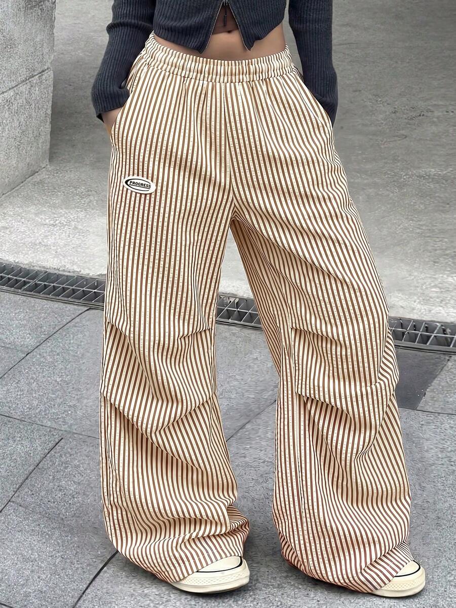 Women's black and white striped wide leg pants featuring an elastic drawstring waistband, side pockets, and a loose straight leg fit.