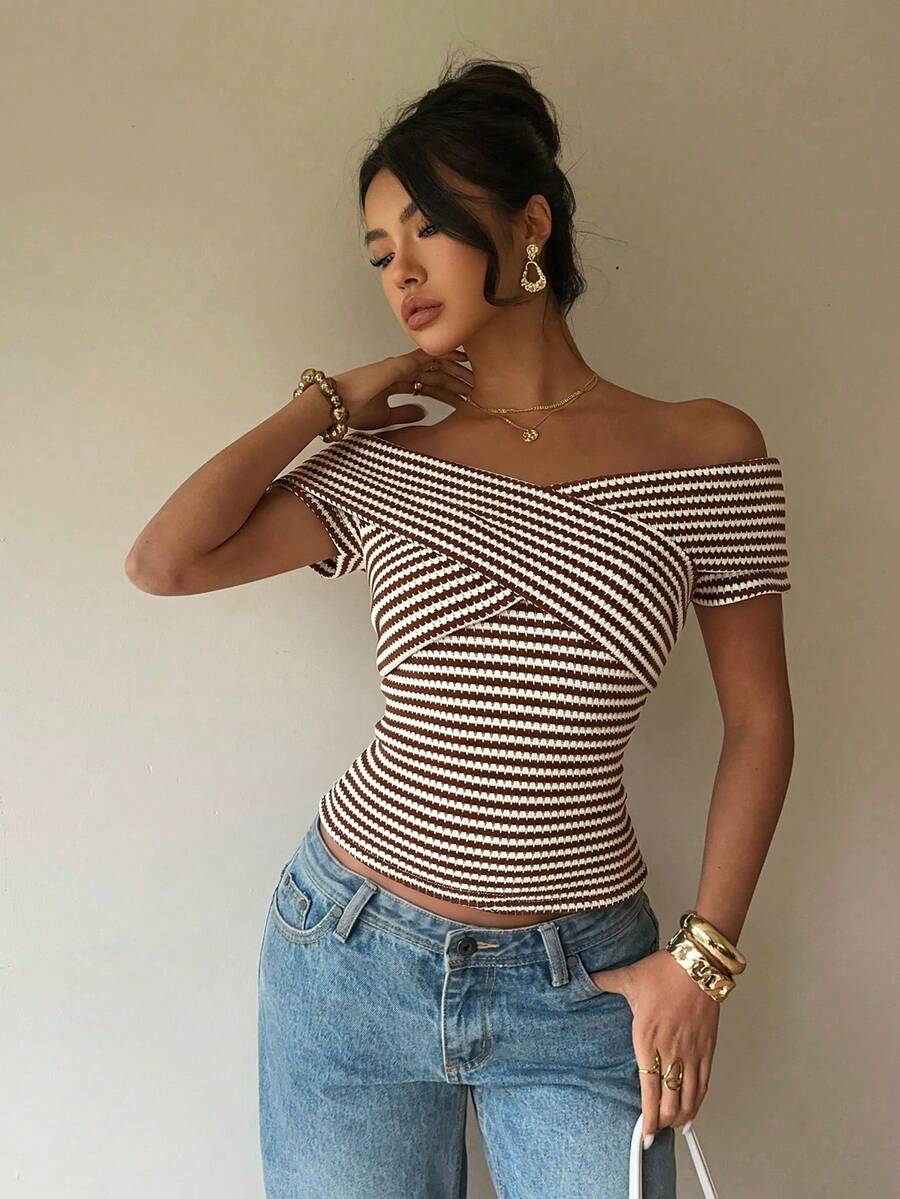 Women's striped short sleeve cold shoulder top featuring a slim fit, criss cross wrap details, and ribbed knitted fabric in apricot.