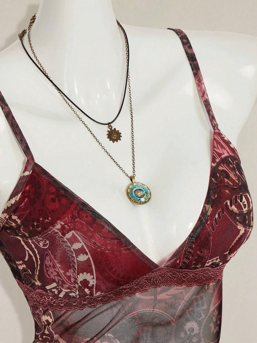 Women's graphic print camisole top featuring thin spaghetti straps, a backless cut, and an asymmetrical hem.