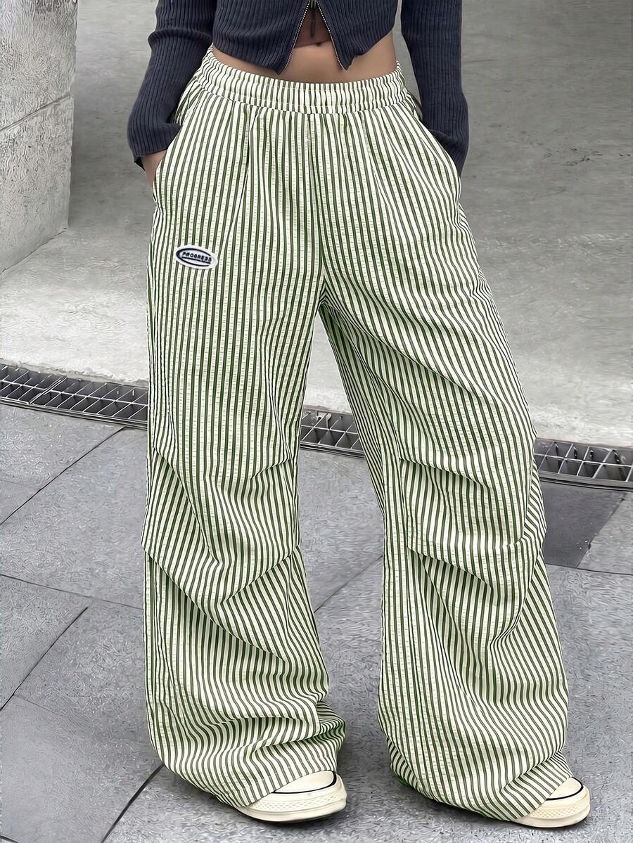 Women's black and white striped wide leg pants featuring an elastic drawstring waistband, side pockets, and a loose straight leg fit.