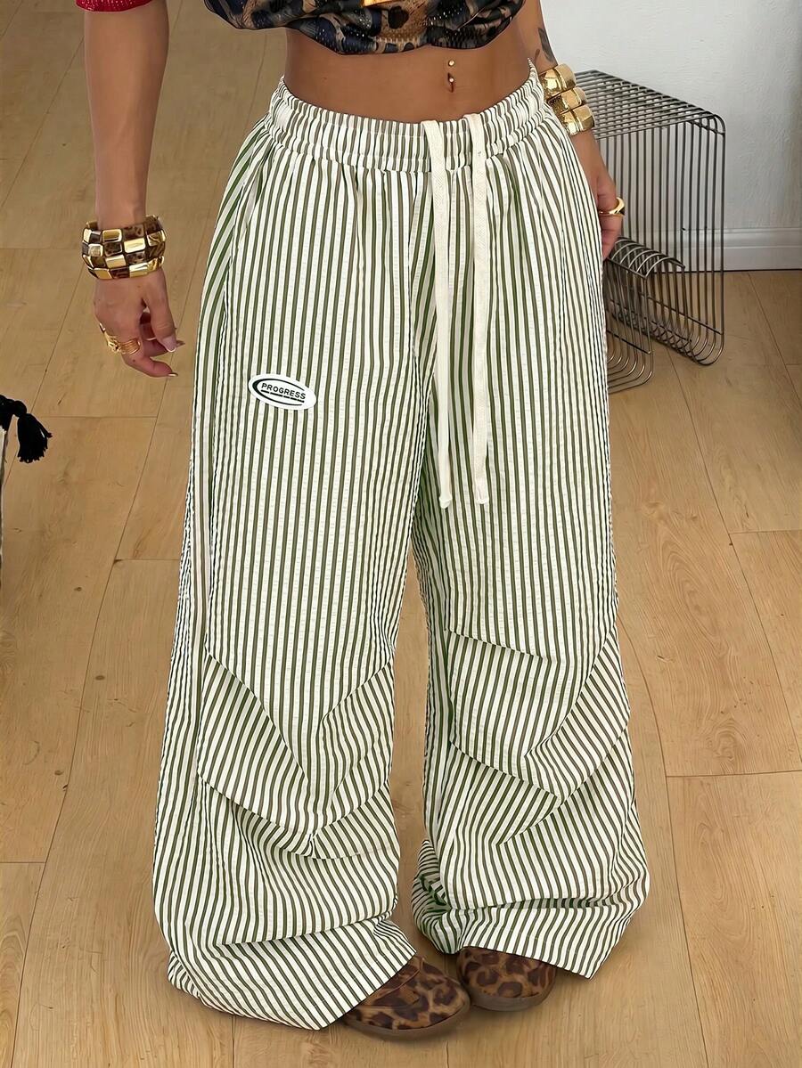 Women's black and white striped wide leg pants featuring an elastic drawstring waistband, side pockets, and a loose straight leg fit.