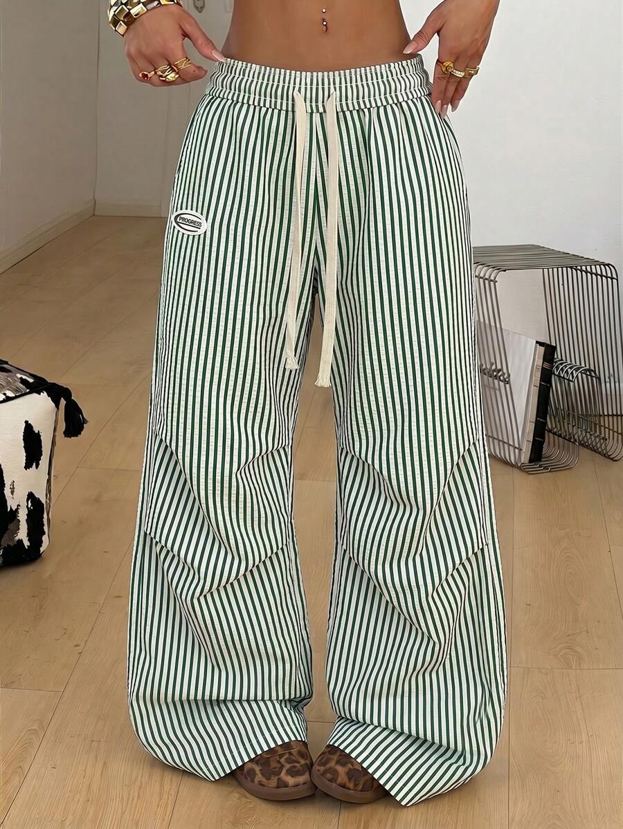 Women's black and white striped wide leg pants featuring an elastic drawstring waistband, side pockets, and a loose straight leg fit.
