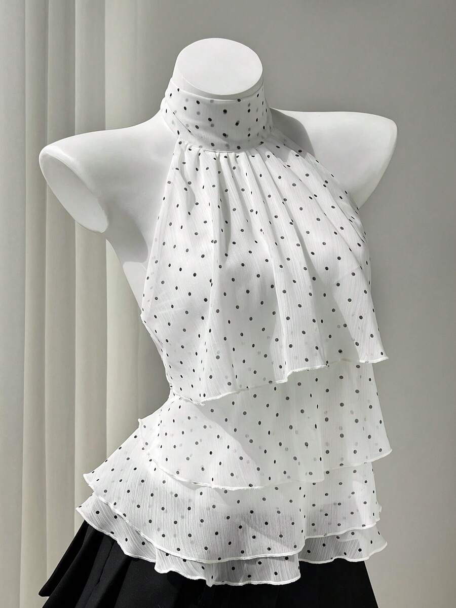 Women's white sleeveless halter neck top featuring pleated fabric, backless tie strap design, and a flared layered ruffle hem.