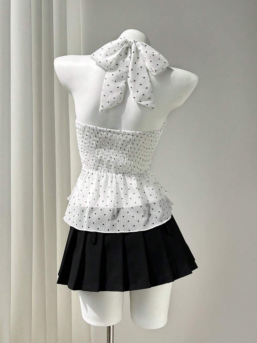 Women's white sleeveless halter neck top featuring pleated fabric, backless tie strap design, and a flared layered ruffle hem.