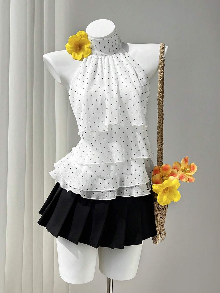 Women's white sleeveless halter neck top featuring pleated fabric, backless tie strap design, and a flared layered ruffle hem.