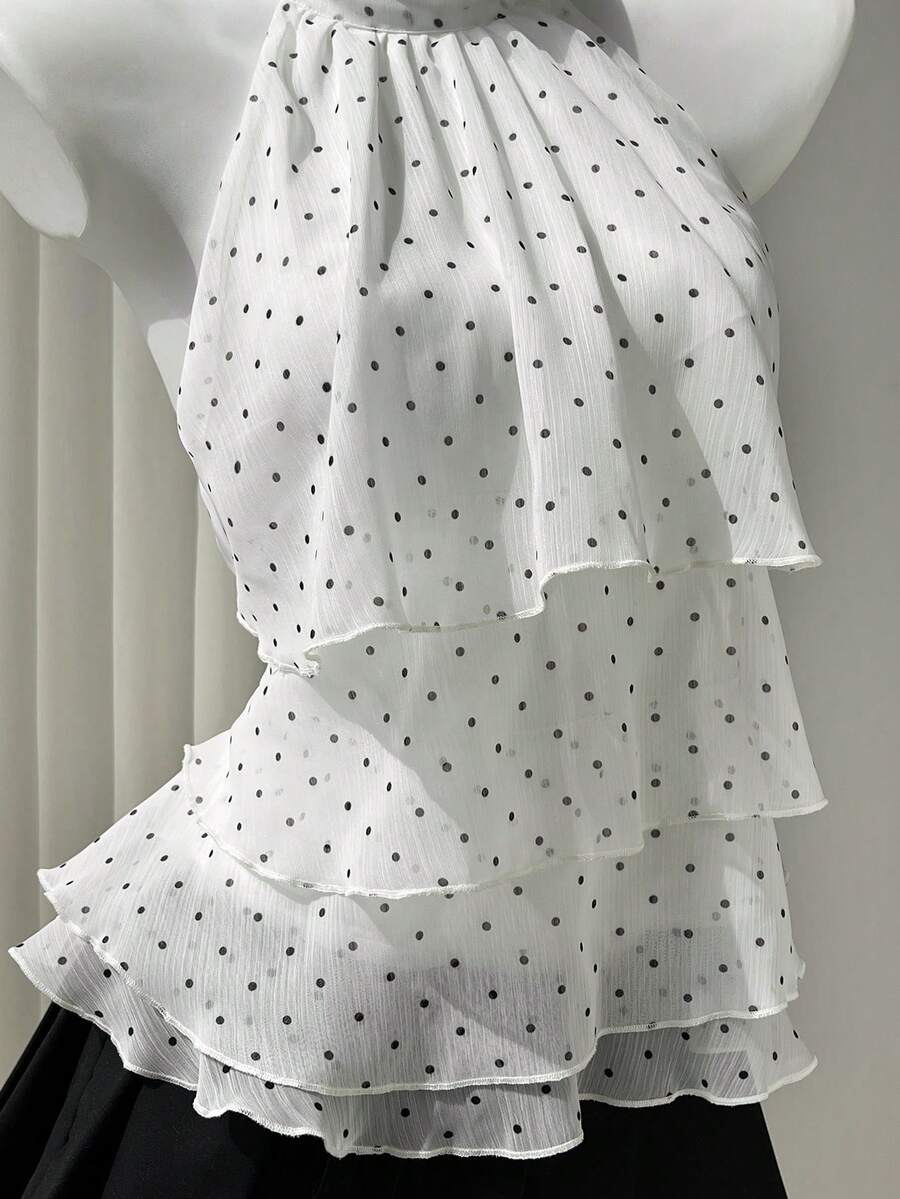 Women's white sleeveless halter neck top featuring pleated fabric, backless tie strap design, and a flared layered ruffle hem.