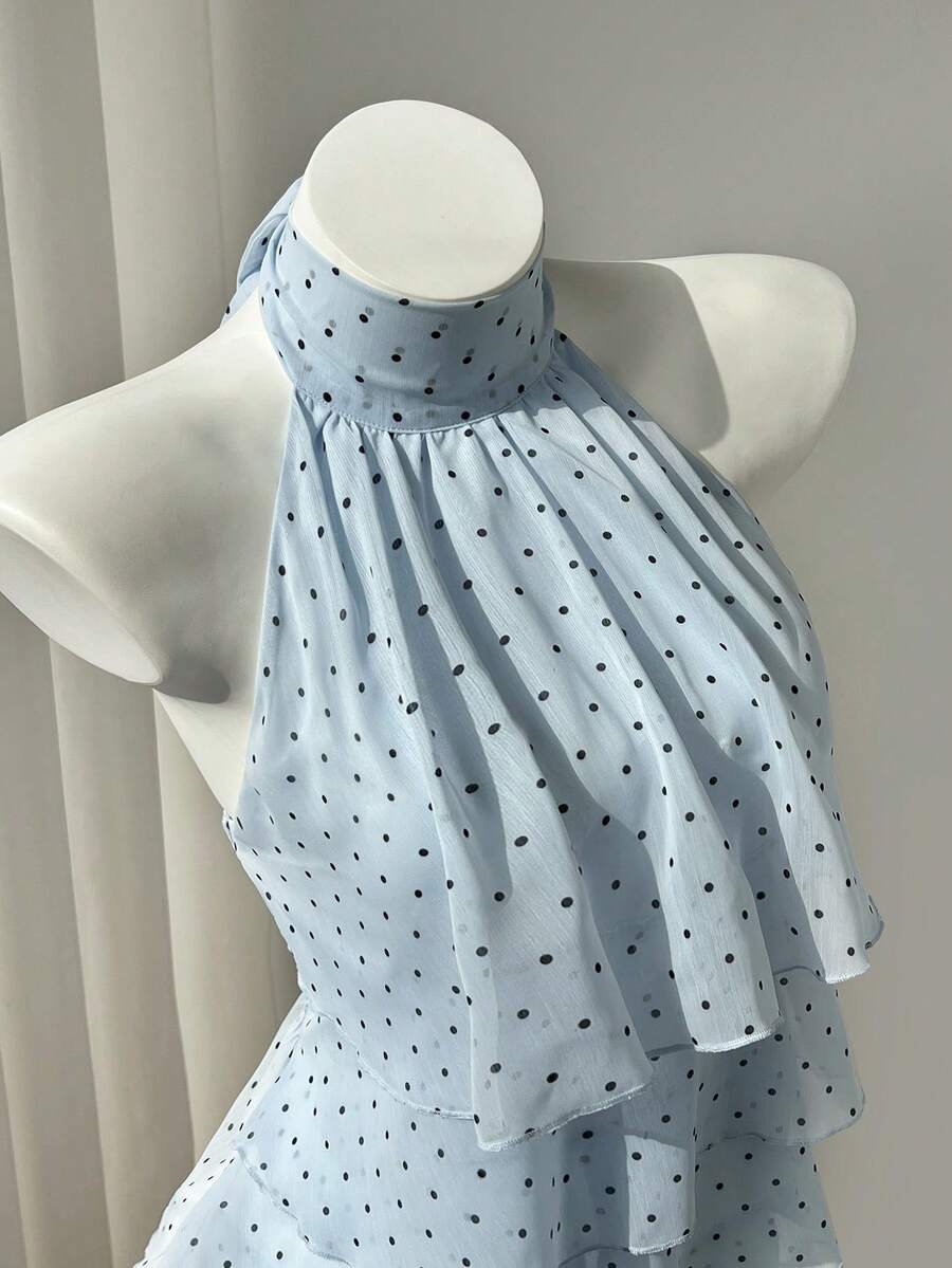 Women's white sleeveless halter neck top featuring pleated fabric, backless tie strap design, and a flared layered ruffle hem.